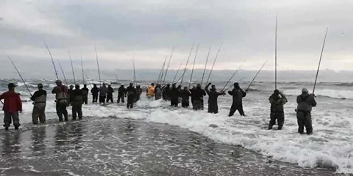 Group fishing in the ocean with rods during overcast weather.